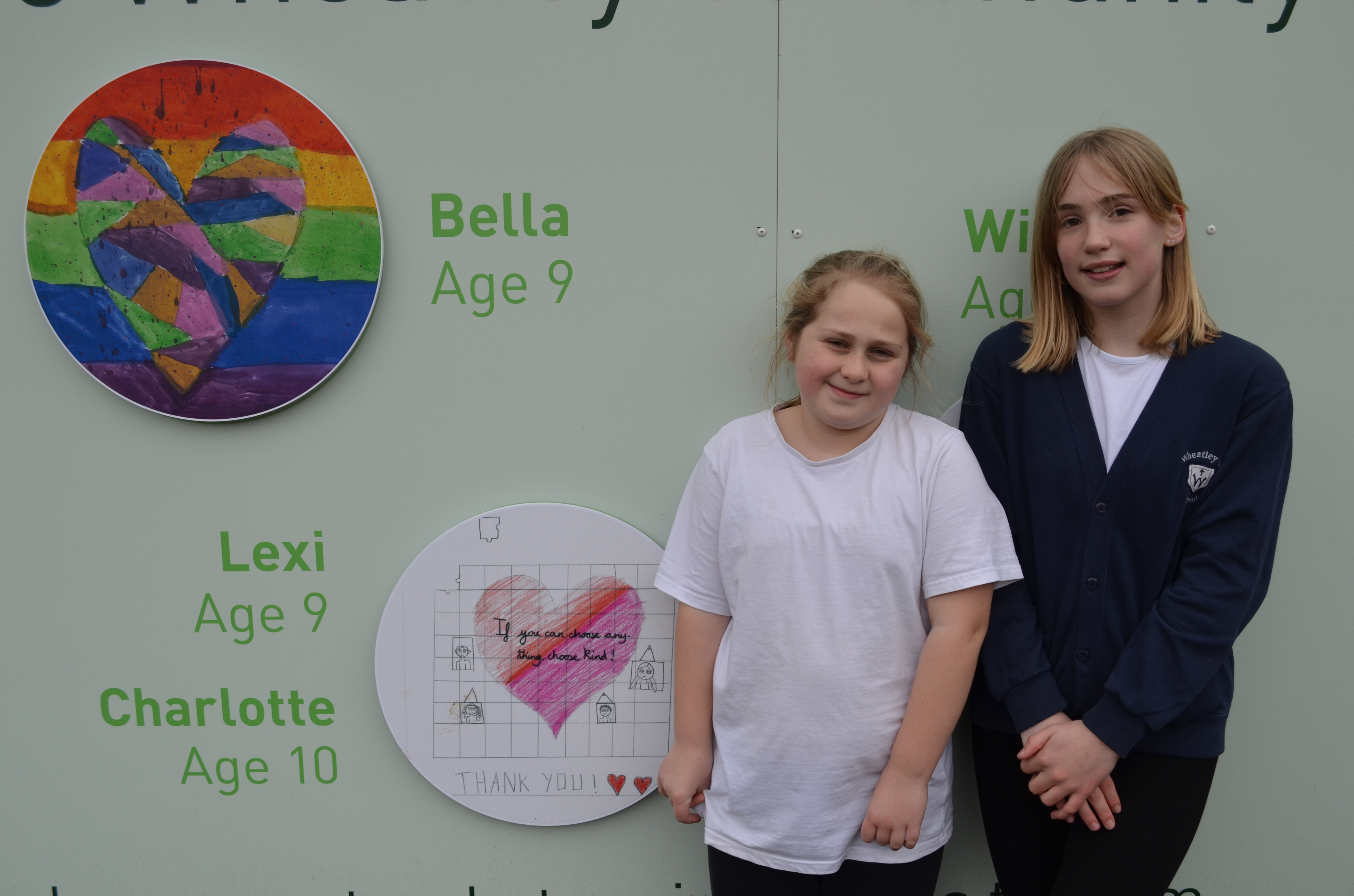 Two girls beside the images of 'caring' they created