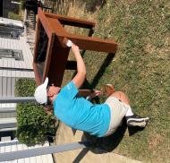 Volunteer staining a raised planter