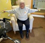A resident at Edwardstow Court completes a seated exercise using therapy balls to support arm strength, flexibility and mobility.