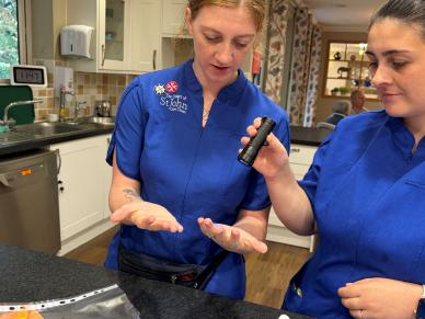 Care home staff use a UV light to check their hands during an Infection Prevention Week activity.