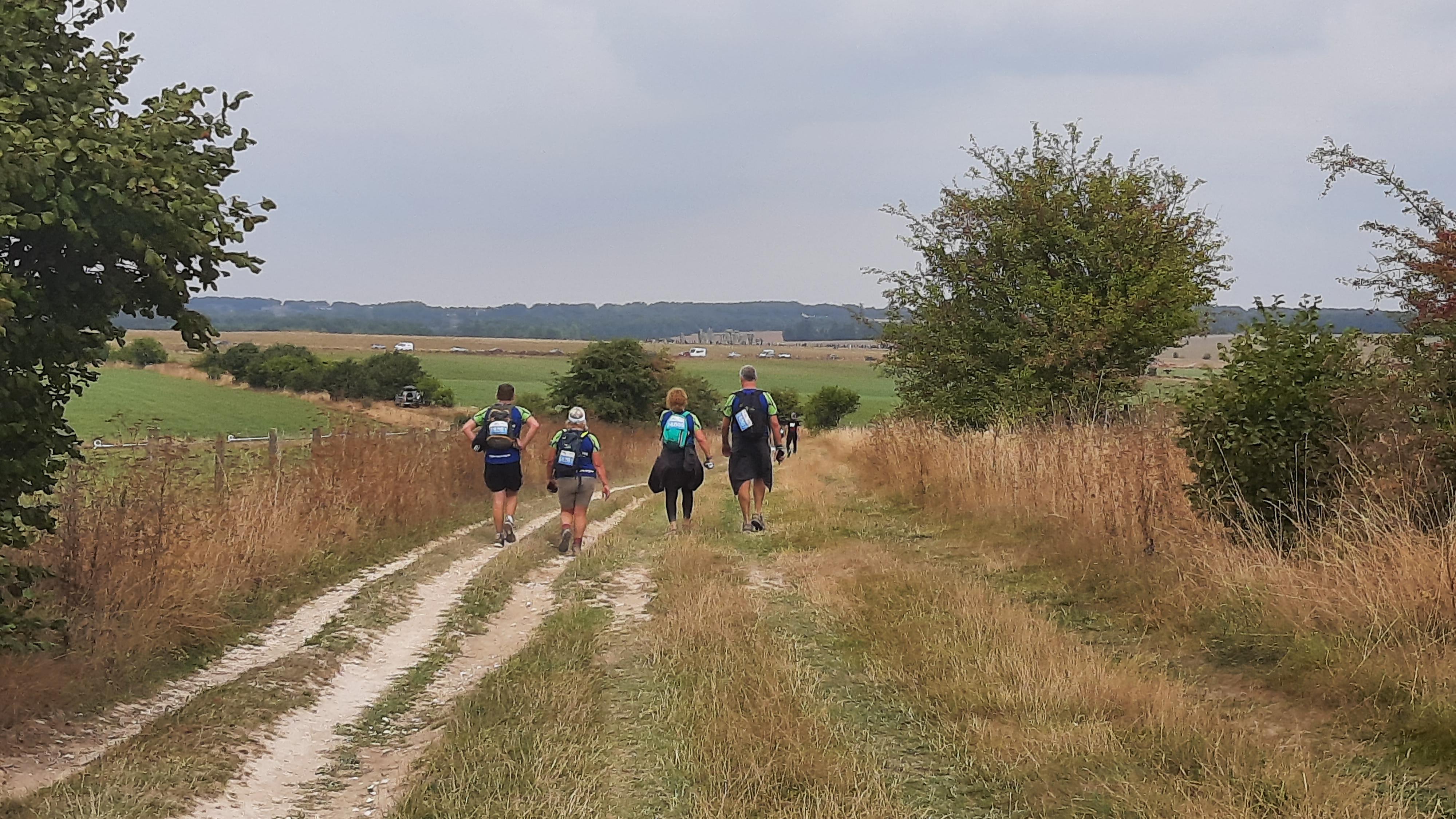 Walkers on a track with Stonehenge in the distance