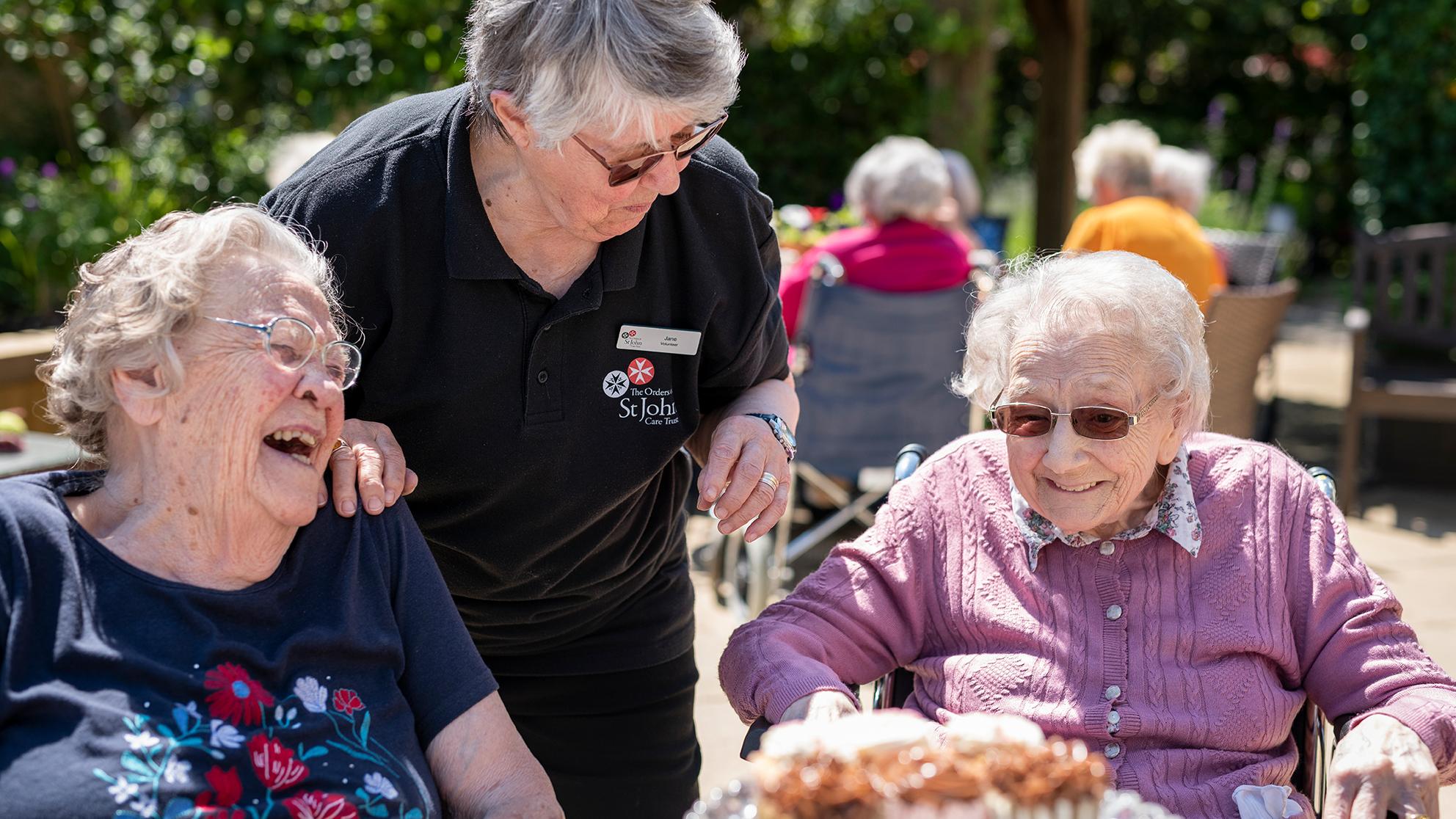 Residents and team member laughing during a sunny garden event
