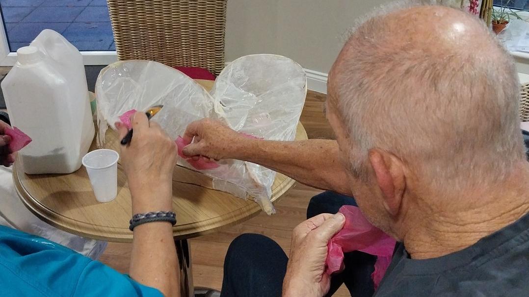 Resident and carer making a paper lantern