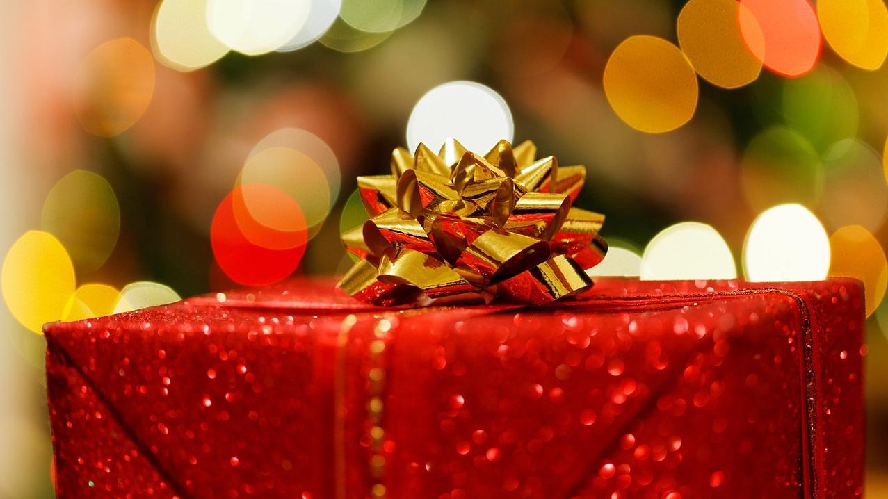 A Christmas gift wrapped in gold paper beneath a Christmas tree