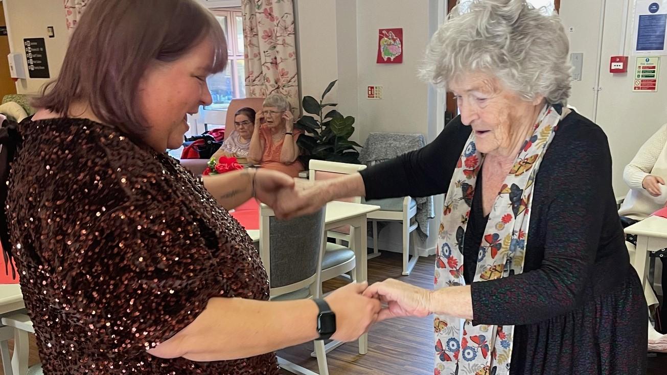 Resident Mary teaches Activities Co-ordinator Joanna Dixon to dance