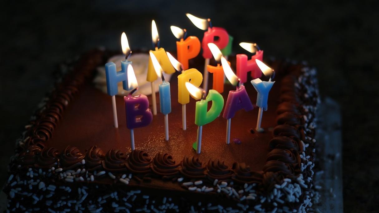 Image shows a birthday cake with lit happy birthday candles