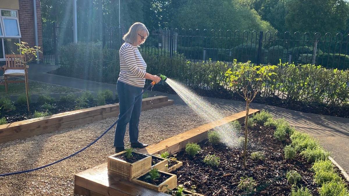Jacquie Tothill, resident watering the new herb planters