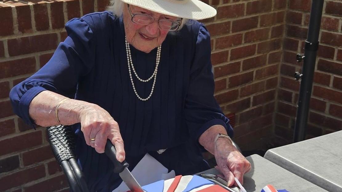 Kathleen Hall cuts the celebratory cake