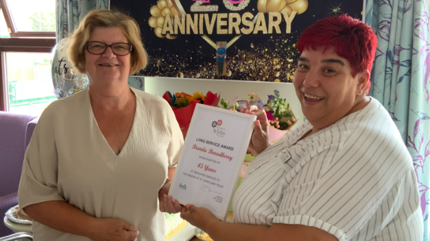 Brenda (L) receives her long service certificate from Home Manager Sara (R)