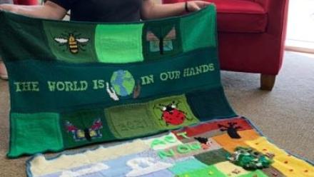 Volunteer Lynn holding the COP26 blanket created in the home