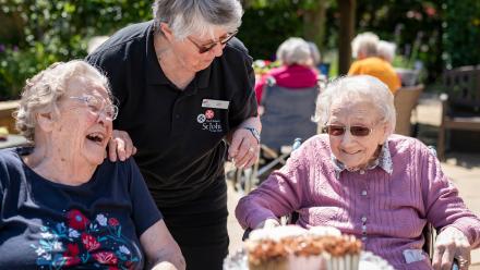 Residents and team member laughing during a sunny garden event