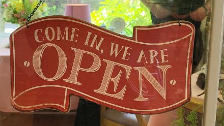 Come in we're open sign in the window of the cafe