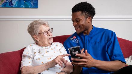 Resident and carer talking together on a sofa
