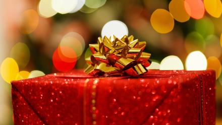 A Christmas gift wrapped in gold paper beneath a Christmas tree