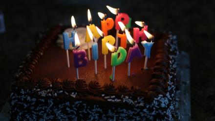 Image shows a birthday cake with lit happy birthday candles